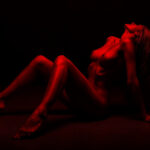 Silhouette of a woman in red light symbolizing the cultural clash between AI girlfriend apps as therapy tools and fantasy experiences